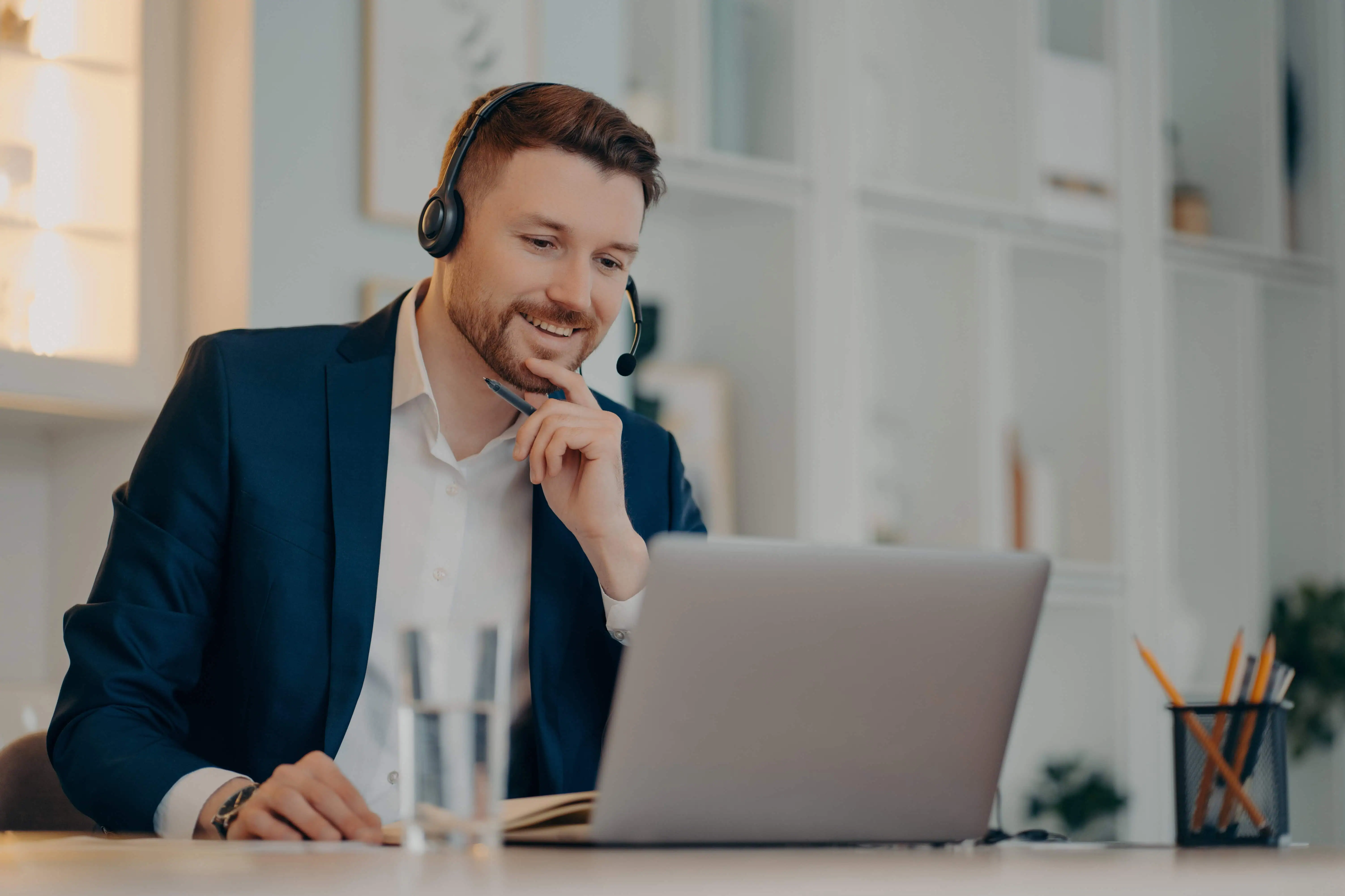 Professional male operator works in callcenter uses headset and laptop computer talks on video call