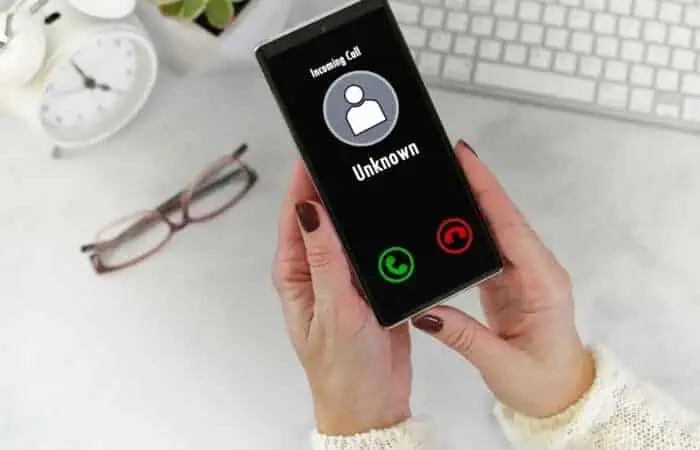 Female hands holding Phone with incoming call from Unknown Caller - fraud scam phishing