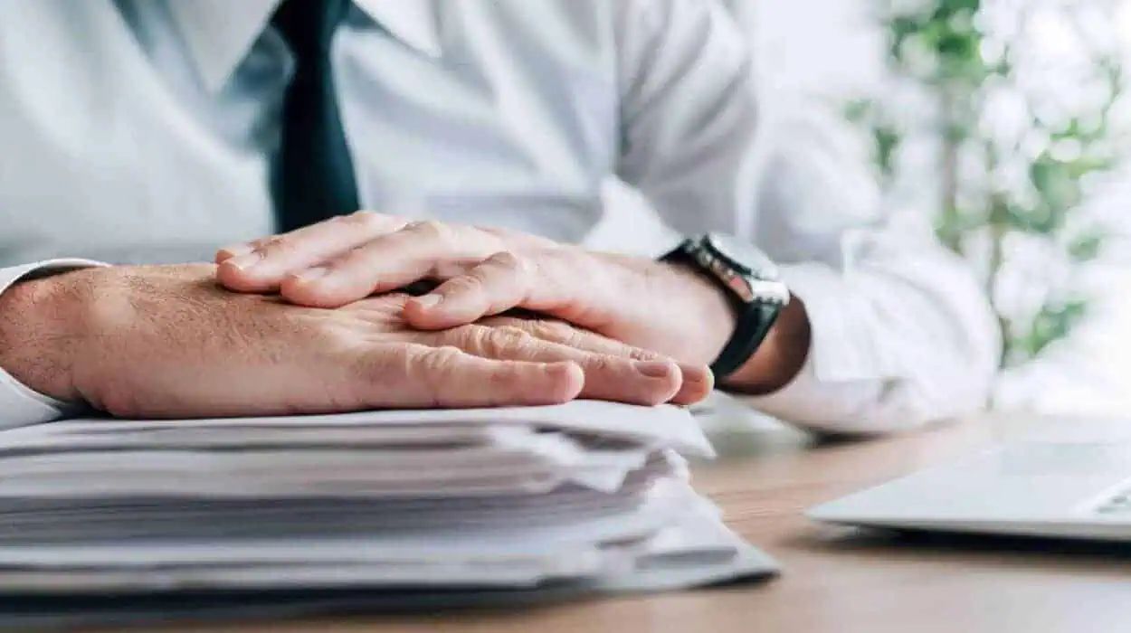 Insurance agent with stack of policy contracts on office desk