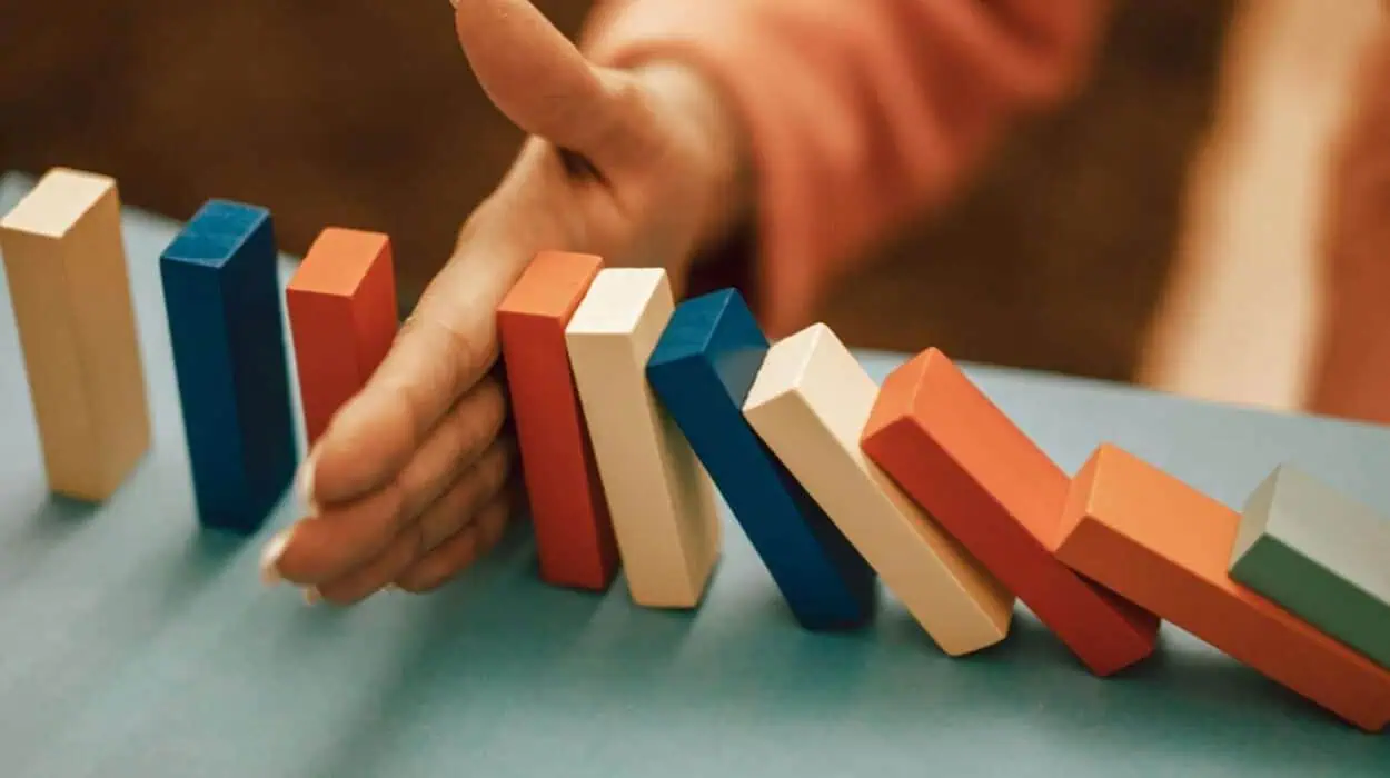 A hand strategically stops falling blue and red domino blocks on a table.